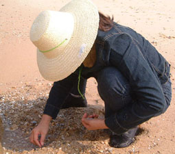 A lady, head down, sifting for pebbles